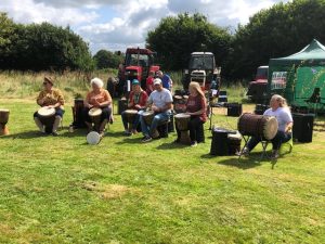 A group of people playing the bongo drums in the sunshine